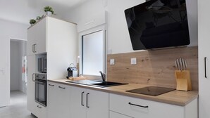 Eine moderne Küche mit weißen Schränken, einer Holz Arbeitsplatte, einer schwarzen Spüle und einem Messerblock.