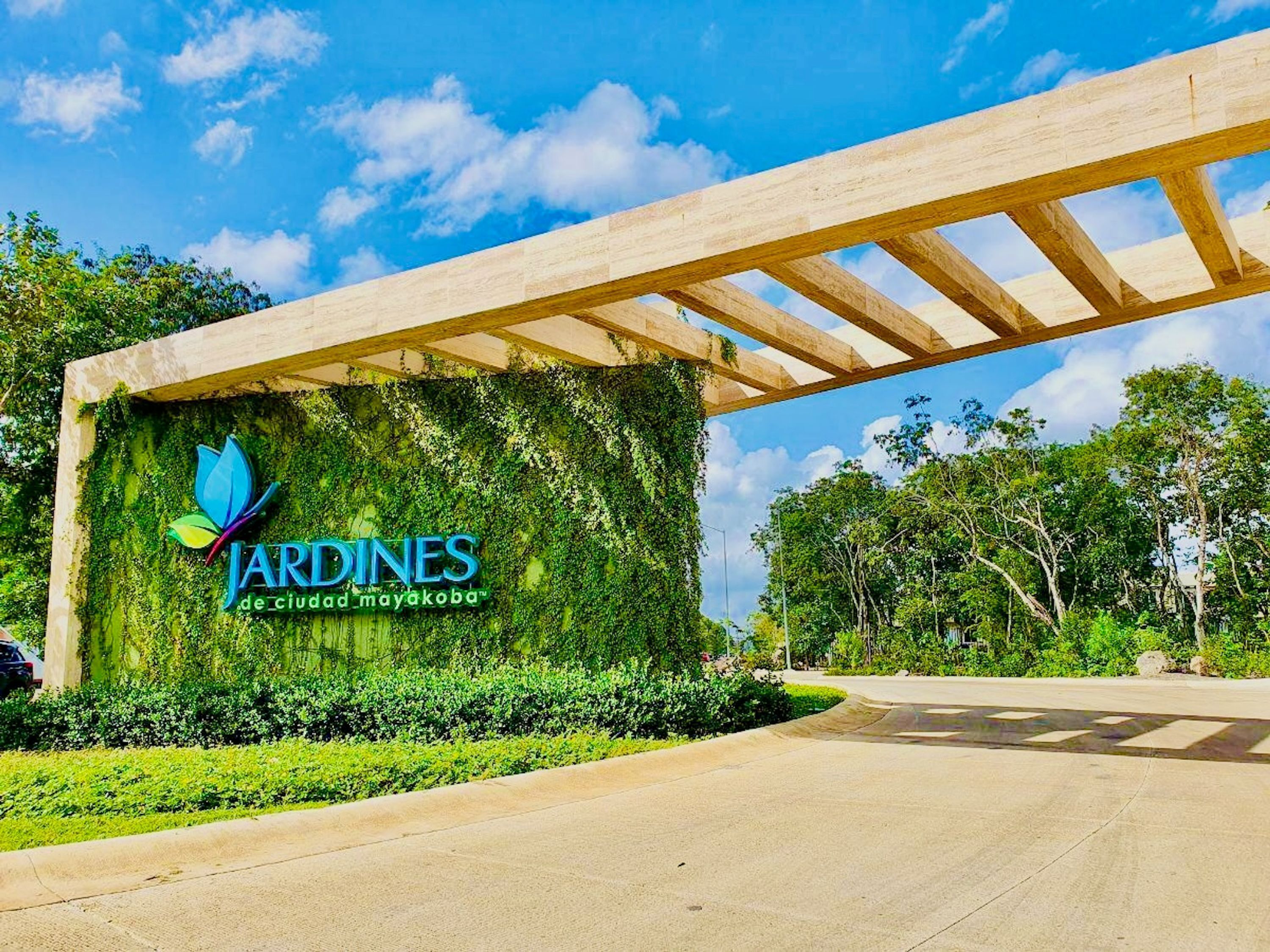 Une entrée de jardin agrémentée d’une pergola, d’un logo et d’une végétation luxuriante.