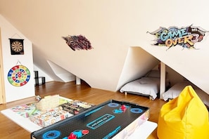 A room with a dartboard, a spinning wheel, a game table, and a wall with a 'GAME OVER' sign.