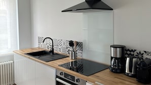 Una cucina moderna con una cappa aspirante nera, un lavello, una macchina da caffè e un bollitore sul piano di lavoro.