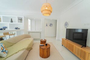 A modern living room with a sofa, a coffee table, a TV on a wooden stand, and a hanging light fixture. - Villa Punique: Villa exceptionnelle avec vue mer (Site arch éologique de Carthage)