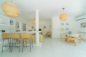A modern interior with a dining area, wicker chairs, a white column, and decorative wall art. - Villa Punique: Villa exceptionnelle avec vue mer (Site archéologique de Carthage)
