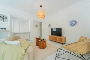 A modern living room with a sofa, a television on a wooden stand, a woven chair, and decorative plates on the wall. - Villa Punique: Villa exceptionnelle avec vue mer (Site archéologique de Carthage)