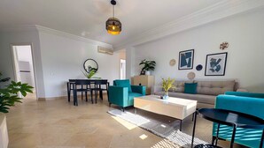 Ein modernes Wohnzimmer mit einer Couch, Sesseln, einem Couchtisch und einem Essbereich mit Tisch und Stühlen.