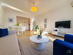 A modern living room with a sofa, a coffee table, a TV, and a dining area with chairs and a table. - Coste Sidi Bou Said A3: Spacious and central (Site archéologique de Carthage)