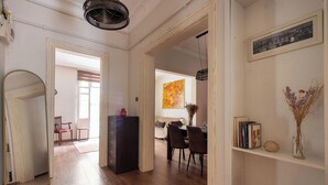 A spacious room with a wooden floor, a dining area with chairs and a table, a bookshelf, and a framed picture on the wall. - Historic & Cozy 2BR Nisantasi Flat w High Ceilings (İstanbul)