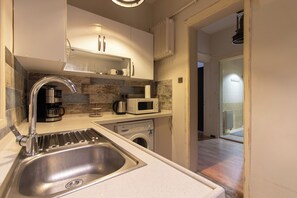 Eine moderne Küche mit Spüle aus Edelstahl, einer Kaffeemaschine, einer Mikrowelle und einer Waschmaschine.