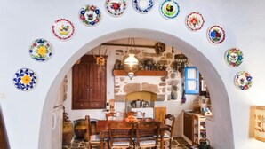 Una cocina rústica con pared de piedra, armarios de madera y suelo de baldosas.