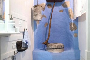 A bathroom with a blue wall, a sink with toiletries, and a towel hanging on the wall.