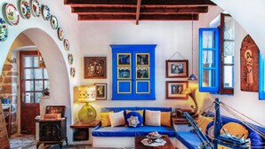 Una habitación acogedora con suelo de piedra, un sofá azul, una mesa de madera y un armario azul con puertas de cristal.