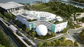 Een modern gebouw met een grote bolvormige structuur, omgeven door groen en palmbomen.