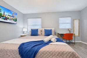 A hotel room with a bed, a desk, a chair, a TV, and a window. - Tranquil Retreat: King Bed, Office, Patio (Lakeland)