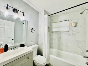 A bathroom with a white sink, mirror, toilet, and bathtub. - Tranquil Retreat: King Bed, Office, Patio (Lakeland)