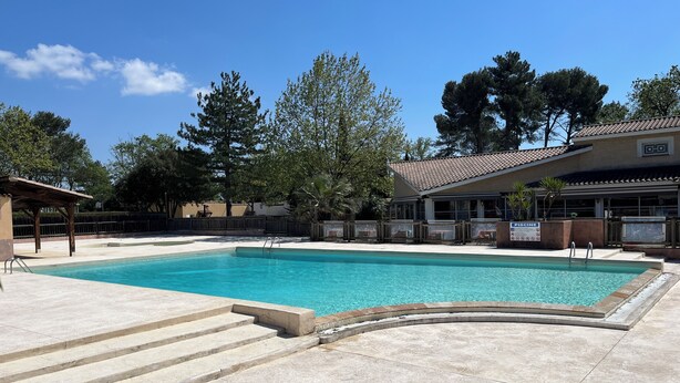 Una piscina con gradini per accedervi, circondata da un portico coperto e un'area salotto all'aperto.