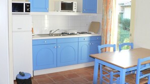 Una cucina compatta con mobili blu, un forno a microonde, un tostapane e un lavello.
