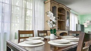Een eetkamer met een houten tafel voor zes personen, een kast en een vaas met witte bloemen.