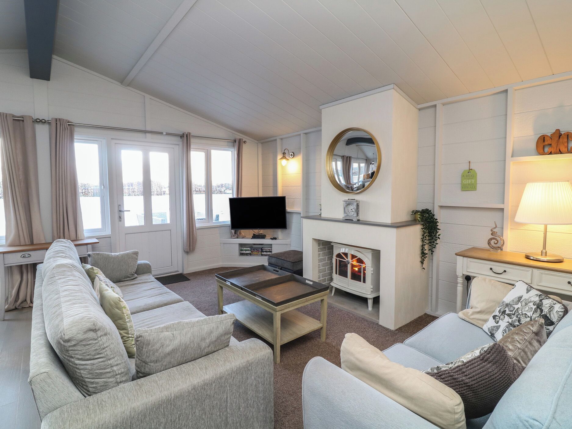 A living room with a sofa set, a TV, a fireplace, and a lamp.