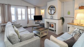 A living room with a sofa set, a TV, a fireplace, and a lamp. - Indulgence Fishing Lodge With Private Hot Tub (Lincoln)