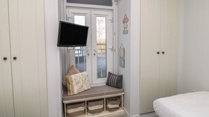 A bedroom with a bed, a bench with storage, a TV, and a door with a window. - Indulgence Fishing Lodge With Private Hot Tub (Lincoln)