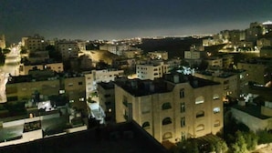 Vista nocturna de una ciudad costera con edificios y una carretera que lleva al mar.