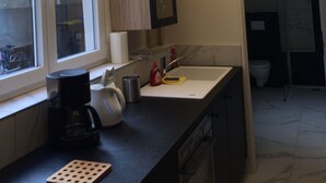 A kitchen with a window, a coffee maker, a sink, and cabinets.
