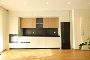 Une cuisine moderne avec des armoires blanches, un comptoir noir et un réfrigérateur noir.