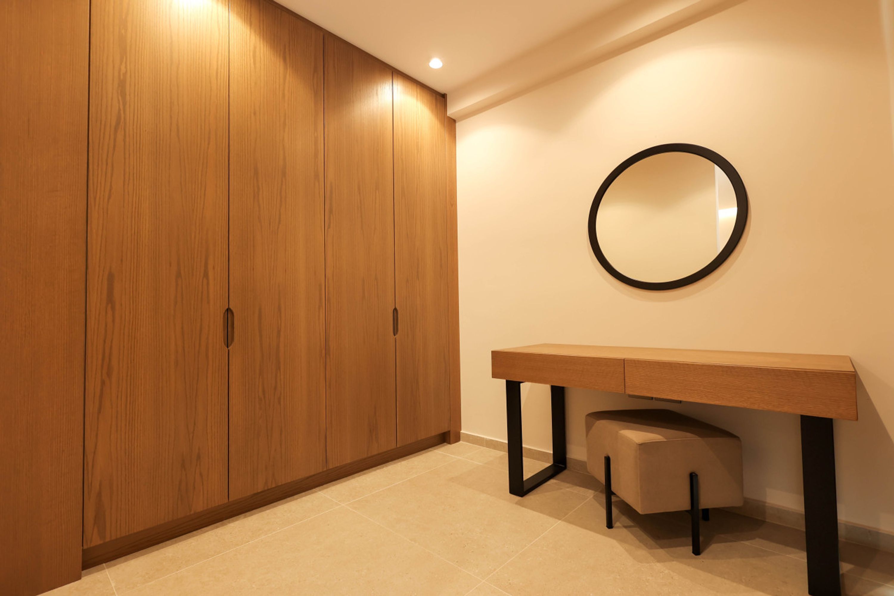 Een kamer met een houten garderobe, een ronde spiegel en een houten bureau met een bankje.