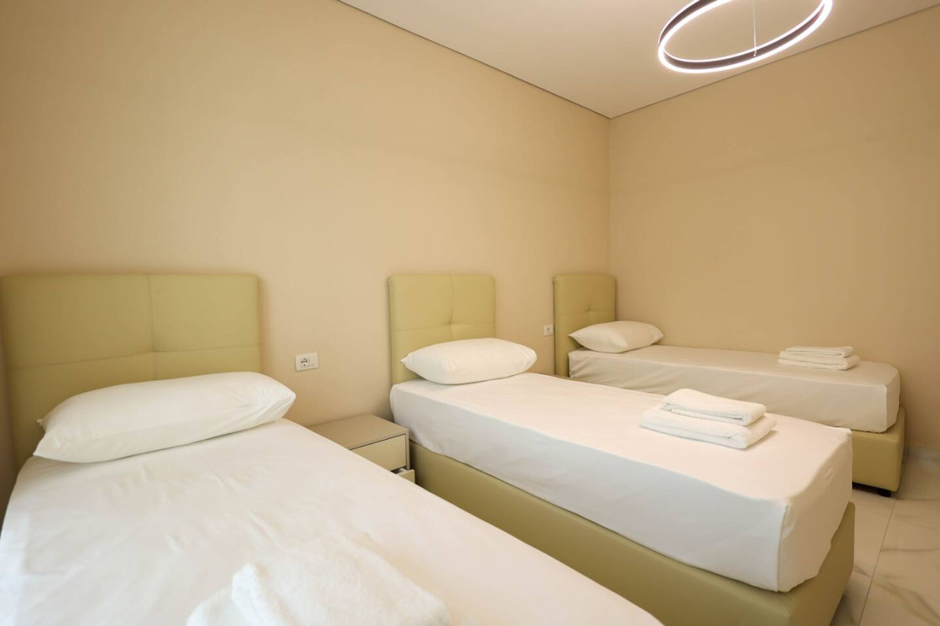 Ett hotellrum med två sängar, var och en med en sänggavel och en kudde. Det finns ett litet nattduksbord med en lampa och en hopvikt handduk på sängen.