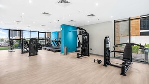 Un gimnasio moderno con diversos equipos de ejercicio, amplias ventanas y un diseño limpio y espacioso.