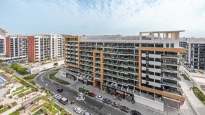 Un edificio residencial moderno de varios pisos con un camino curvo y un área de estacionamiento.