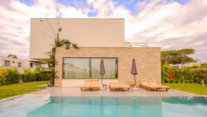 Zona de piscina moderna amb una piscina nítida, gandules i ombrelles.