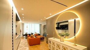 Ein modernes Wohnzimmer mit einer Couch, einem Essbereich und einer Küche mit einem großen Spiegel.
