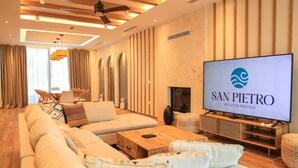 A modern living room with a large flat-screen TV, a sofa set, a wooden coffee table, and a fireplace. - SanPietro Elite Signature Villa (Plazhi San Pietro)