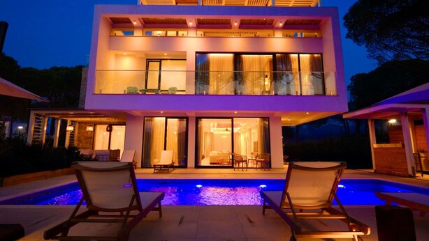 A modern two-story house with a swimming pool, outdoor seating, and large windows. - SanPietro Elite Signature Villa (Plazhi San Pietro)