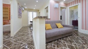 Ein modernes Wohnzimmer mit einem grauen Sofa, gelben Kissen und einem Boden mit Marmoroptik.