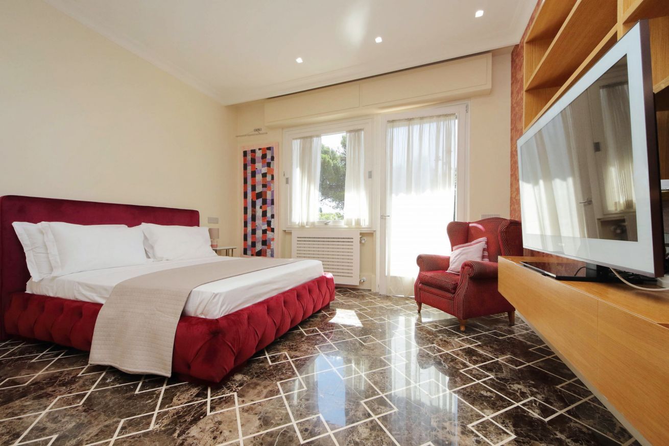 Une chambre d’hôtel avec un grand lit, une télévision et un fauteuil rouge.