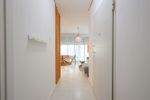 Un couloir menant à une chambre à coucher qui contient un lit, une chaise et une table.