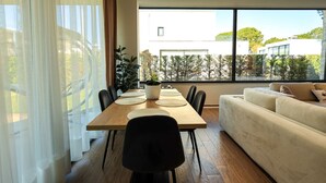 Een moderne eetruimte met een houten tafel, stoelen en een witte bank.