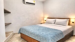 Ein Schlafzimmer mit einem Bett, einer Wand-Klimaanlage und einem Nachttisch mit Lampe.