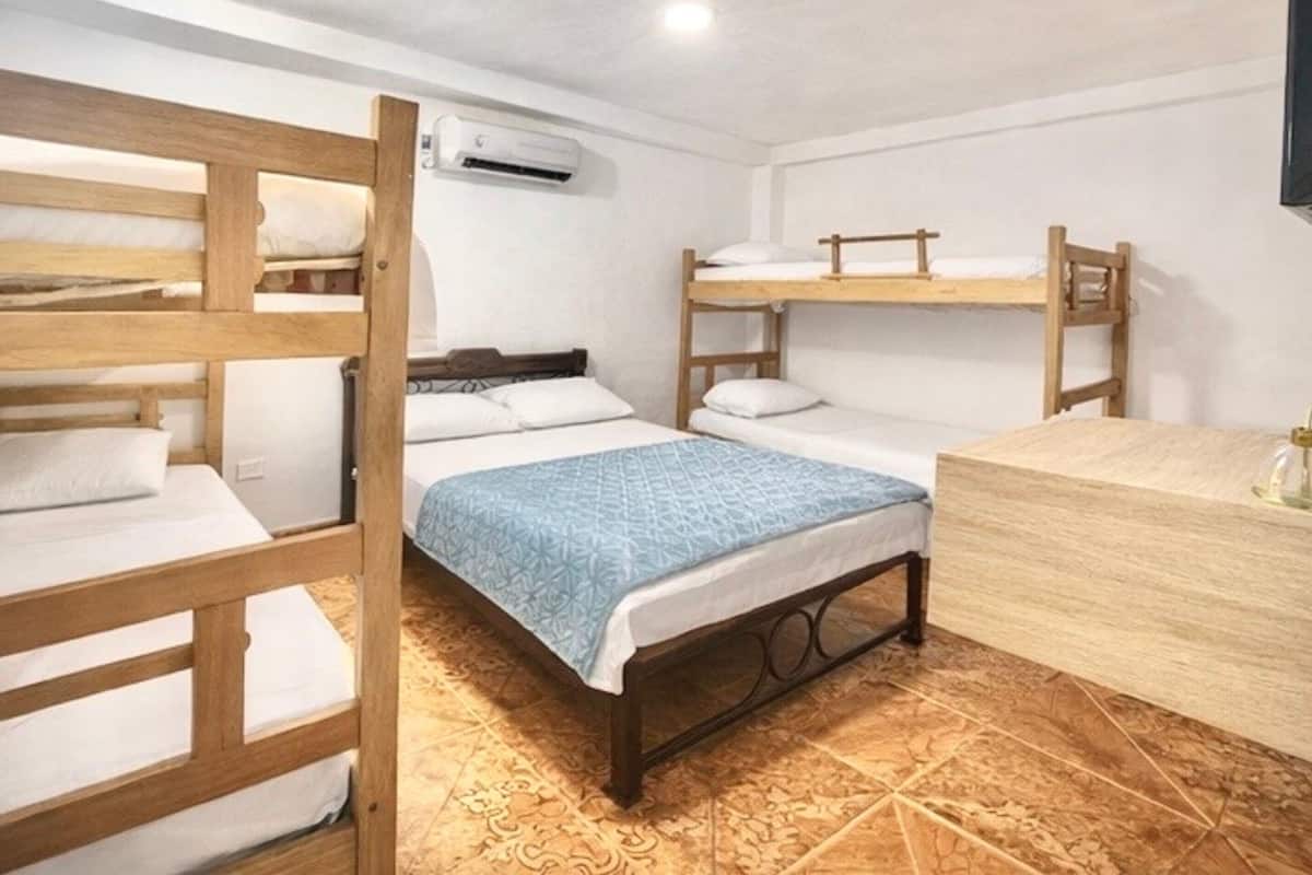 Una habitación con literas, un escritorio de madera y un baño con espejo.