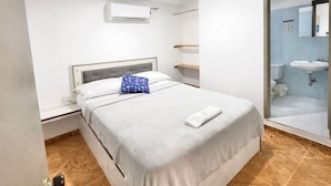Ein Hotelzimmer mit Bett, einem Badezimmer mit Dusche und einer weißen Klimaanlage an der Wand.