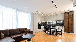 Ein modernes Wohnzimmer mit einem braunen Ledersofa, einem runden goldenen Tisch und einem Essbereich mit Holzkästen und einem schwarzen Tisch.