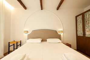 Ein Hotelzimmer mit einem großen Bett, zwei Nachttischlampen, einem Holznachttisch und einem Bild an der Wand.