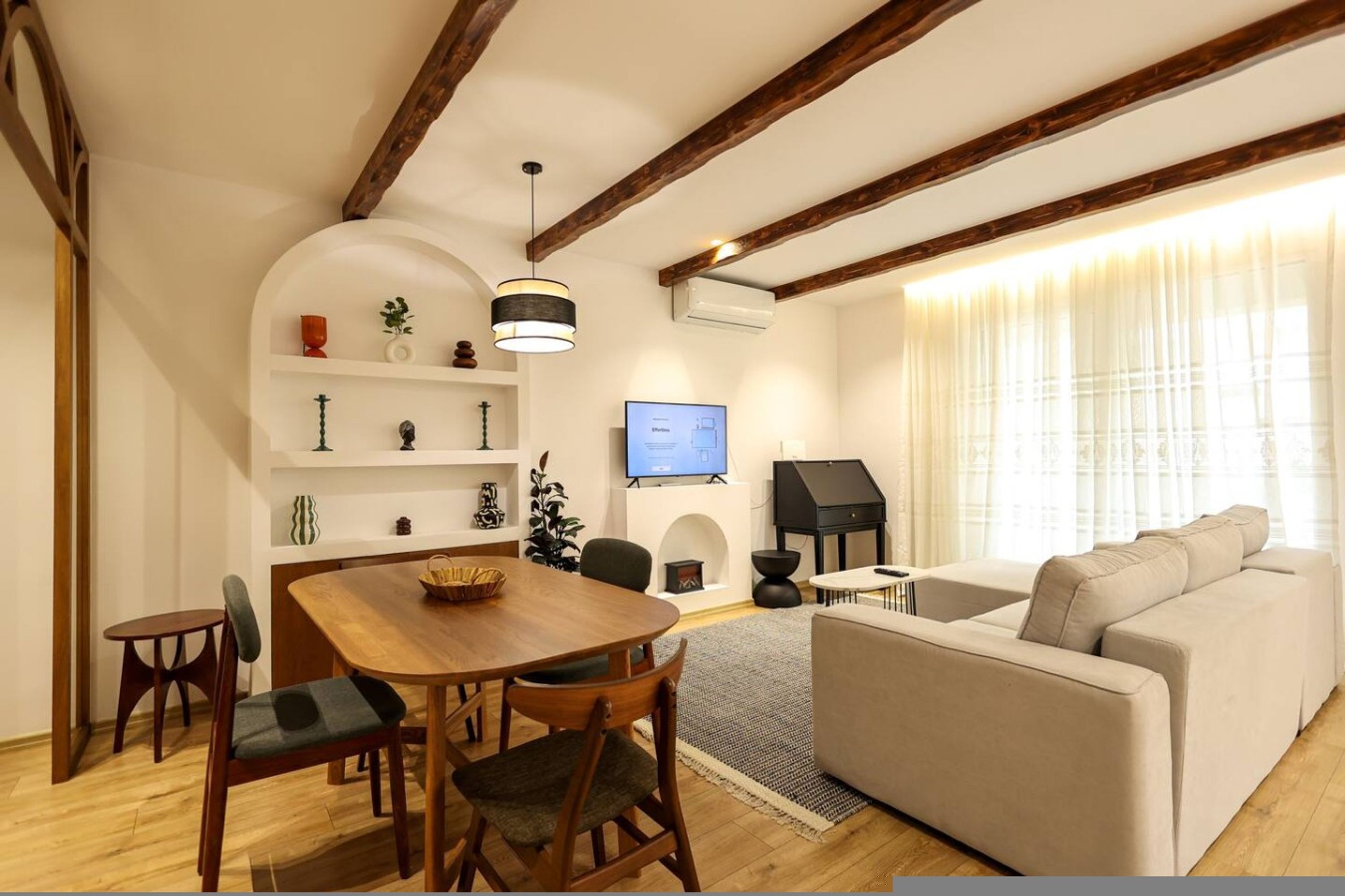 Een woonkamer met een houten eettafel, stoelen, een bank en een televisie.