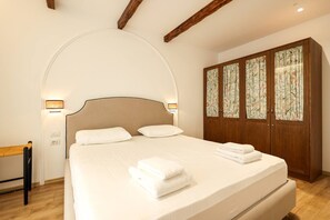 A bedroom with a large bed, a wooden wardrobe, and a bench. - Premium Apartment with Garden (Plazhi San Pietro)