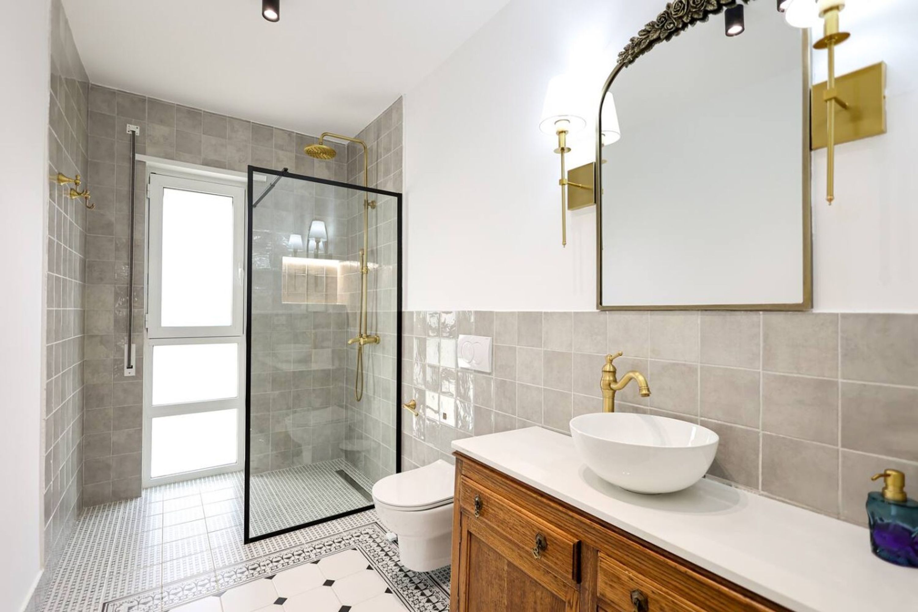 Un baño moderno con cabina de ducha de vidrio, un lavabo blanco y un espejo grande.