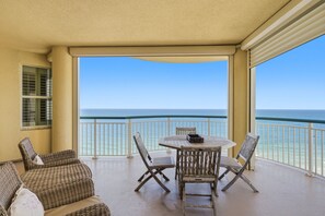 A balcony with a view of the ocean, wicker furniture, and a table with chairs. - Beach Colony Tower Penthouse 16D - New Listing! Gulf Front! (Perdido Key)