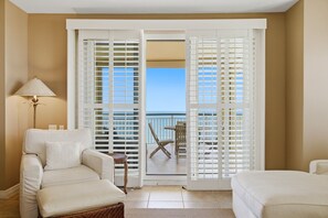 Une chambre d’hôtel avec un balcon, un canapé, un fauteuil et un lit.