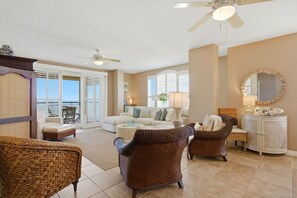 A spacious living room with a balcony, wicker furniture, a white sofa, and a ceiling fan. - Beach Colony Tower Penthouse 16D - New Listing! Gulf Front! (Perdido Key)