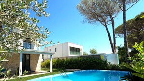 Una casa moderna con piscina, rodeada de vegetación y árboles.